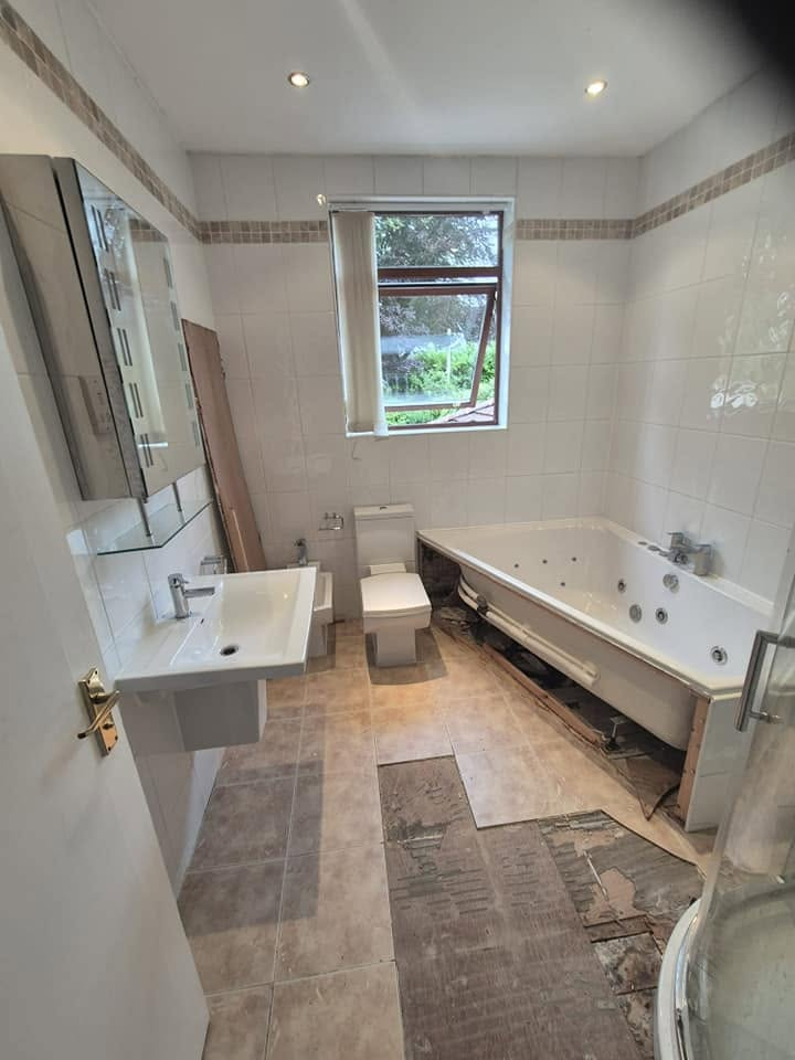 Old white tiled bathroom with dated bath, basin and floor stripped back before renovation