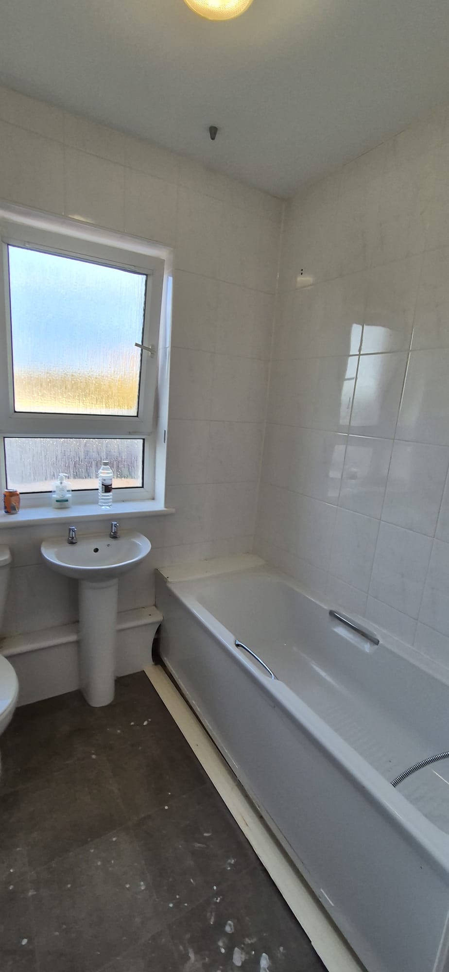 Old bathroom with cream tiles, pedestal basin and dated bath before renovation