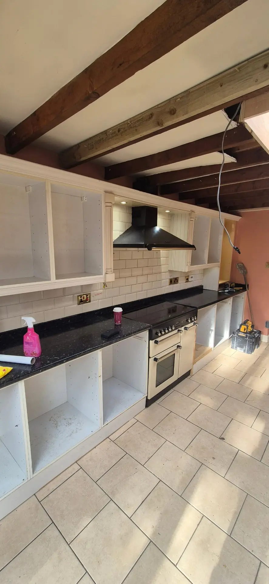 Old kitchen run stripped back with black speckled worktops and exposed carcasses before renovation