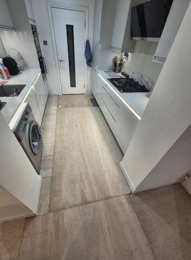 Galley kitchen with bare plywood subfloor before tiling